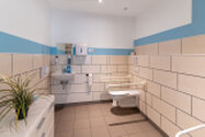 gefliestes Bad mit Waschbecken Toilette und Sitzdusche